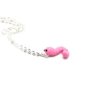 Pink snake-shaped charm on a silver chain against a white background