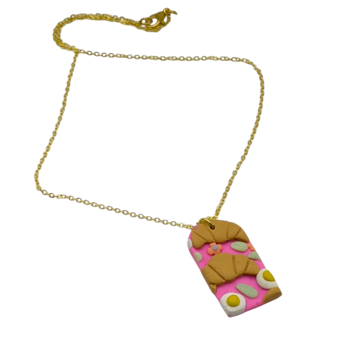 Pink pendant necklace with breakfast food  on resting on a white background 