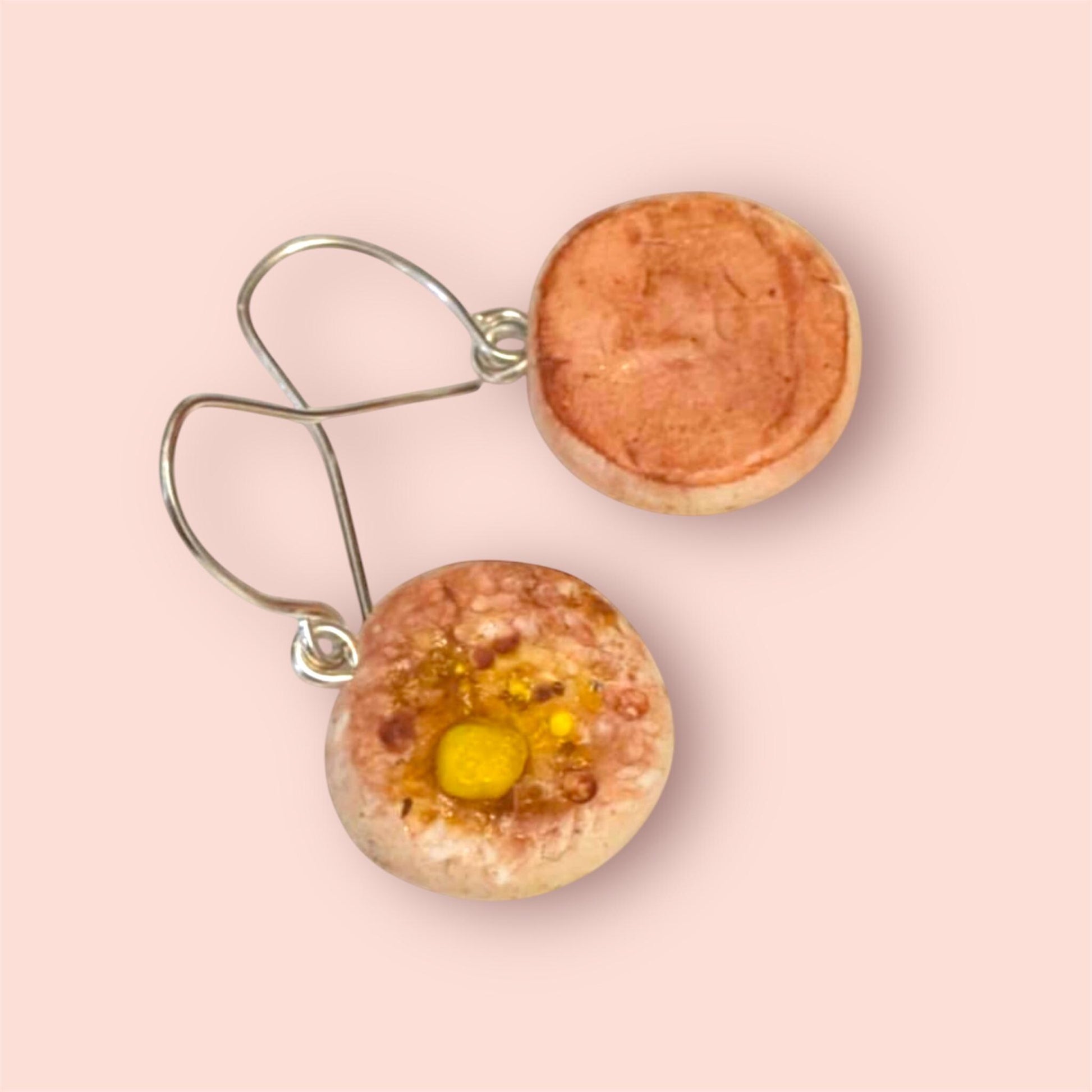 Crumpet earrings with a yellow centre on a pink background