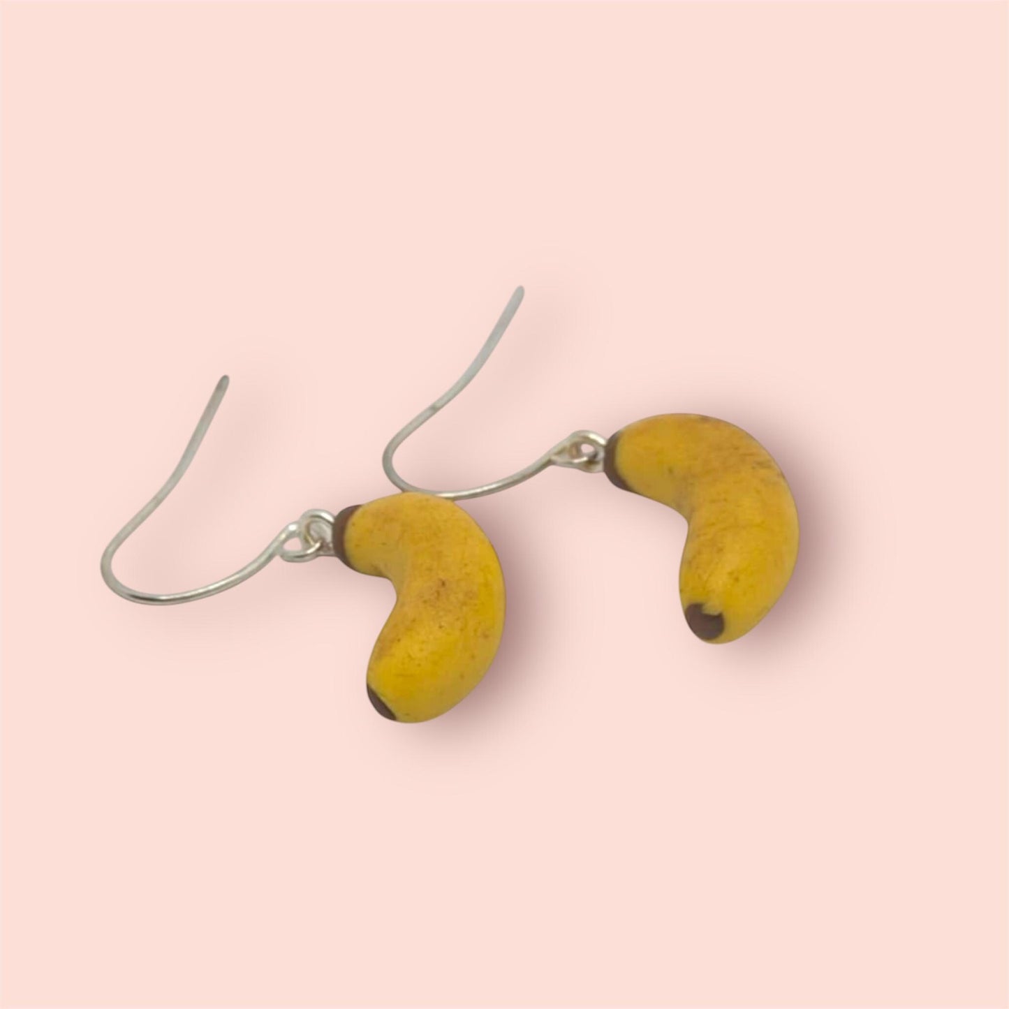 Banana-shaped earrings on a pink background