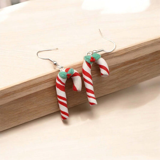 Candy cane-shaped earrings on a wooden surface