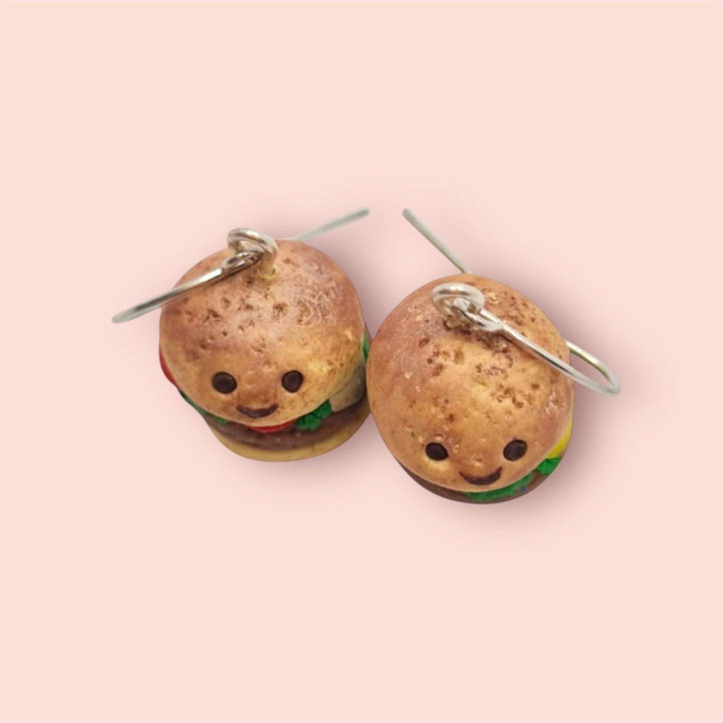 Burger-shaped earrings on a pink background