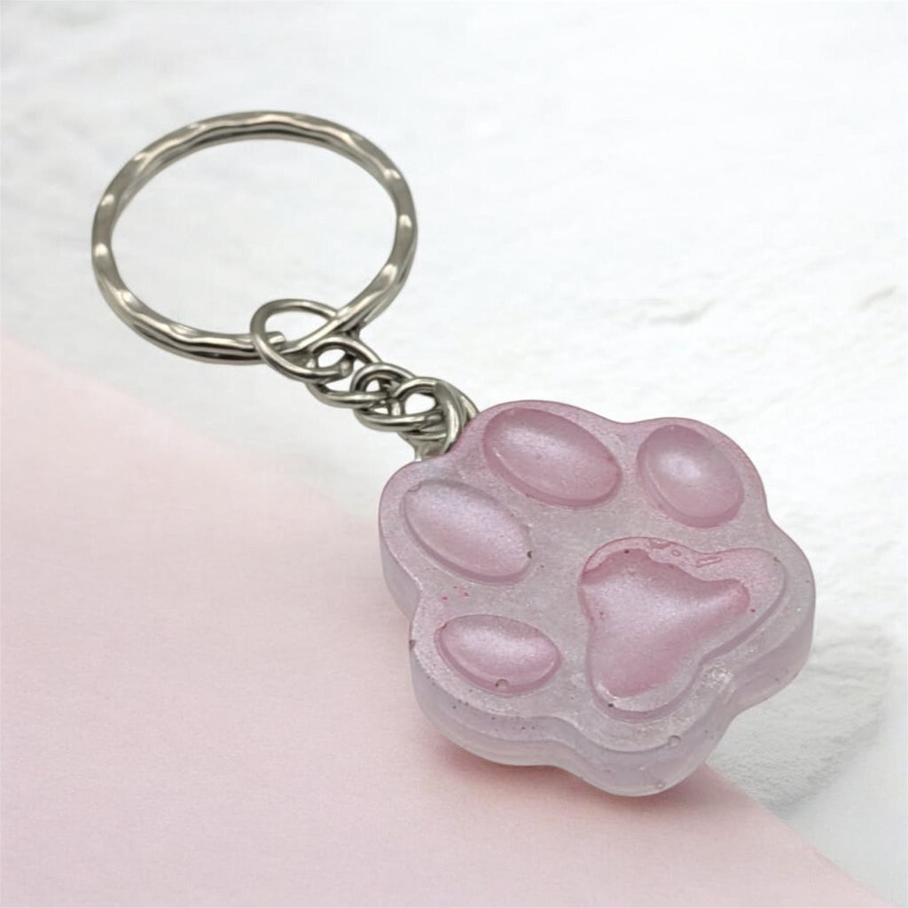 Pink resin paw print keychain on light pink background, handmade in the UK