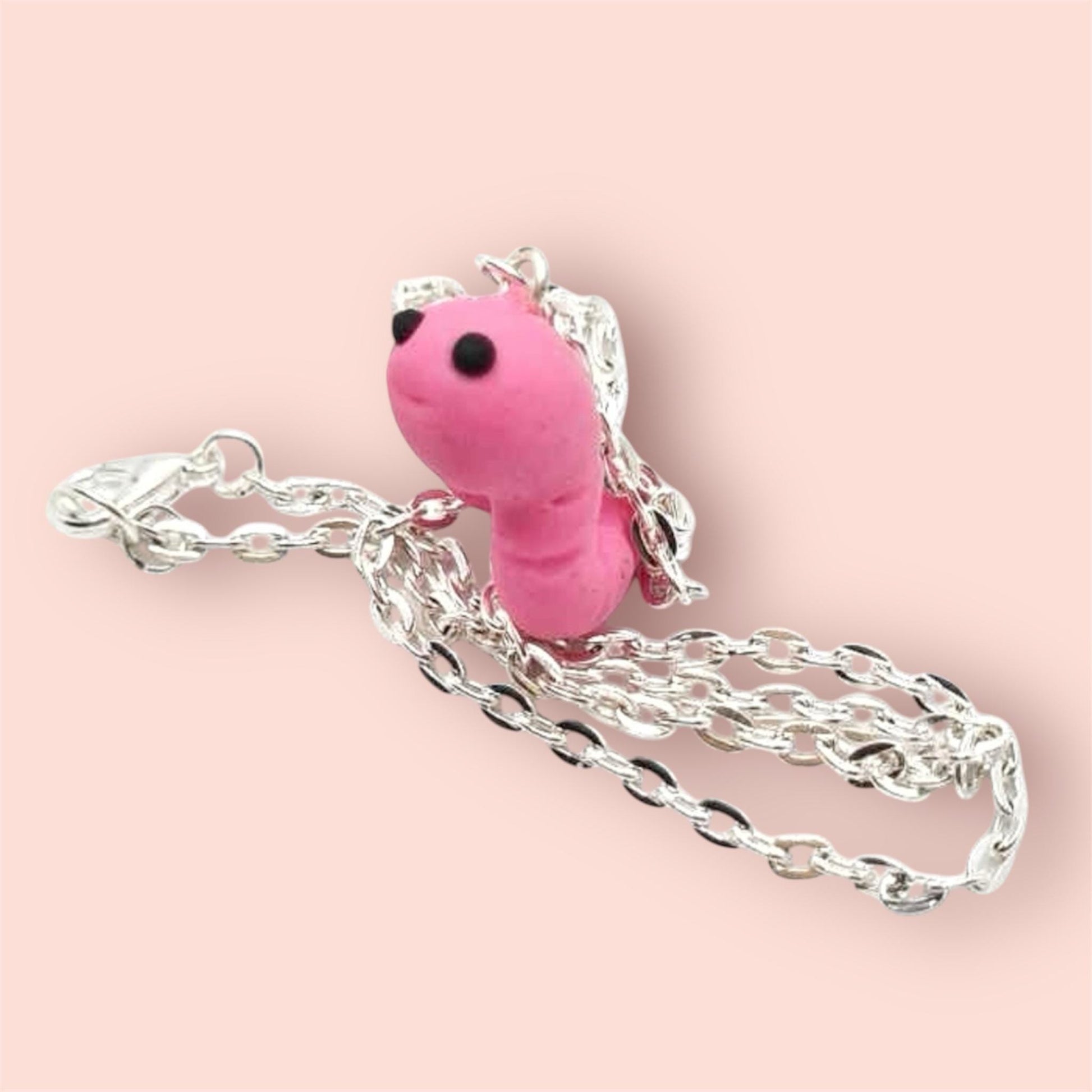 Pink cute worm pendant on a silver chain pink background 