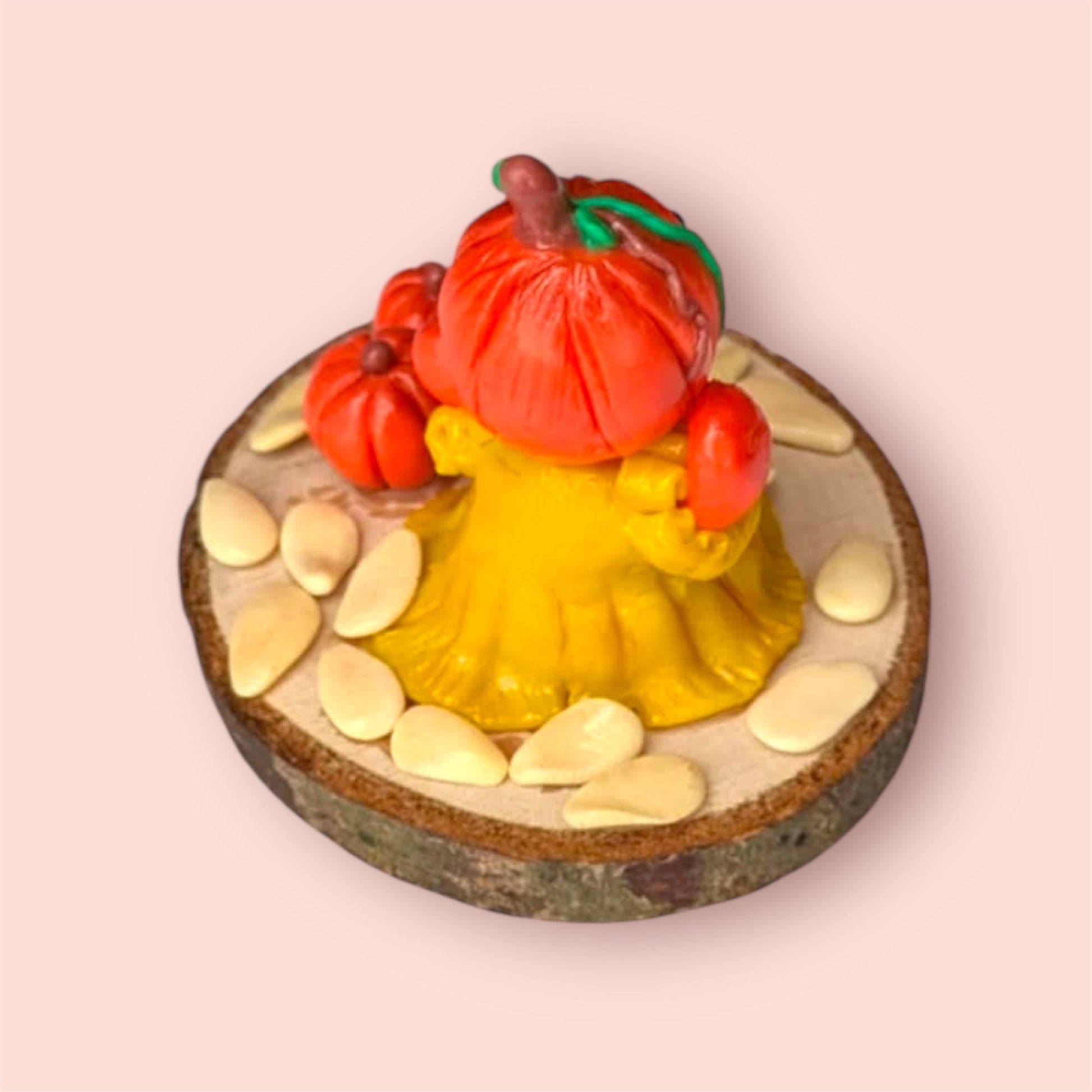 Back of pumpkin figurine on wooden base light pink background. 