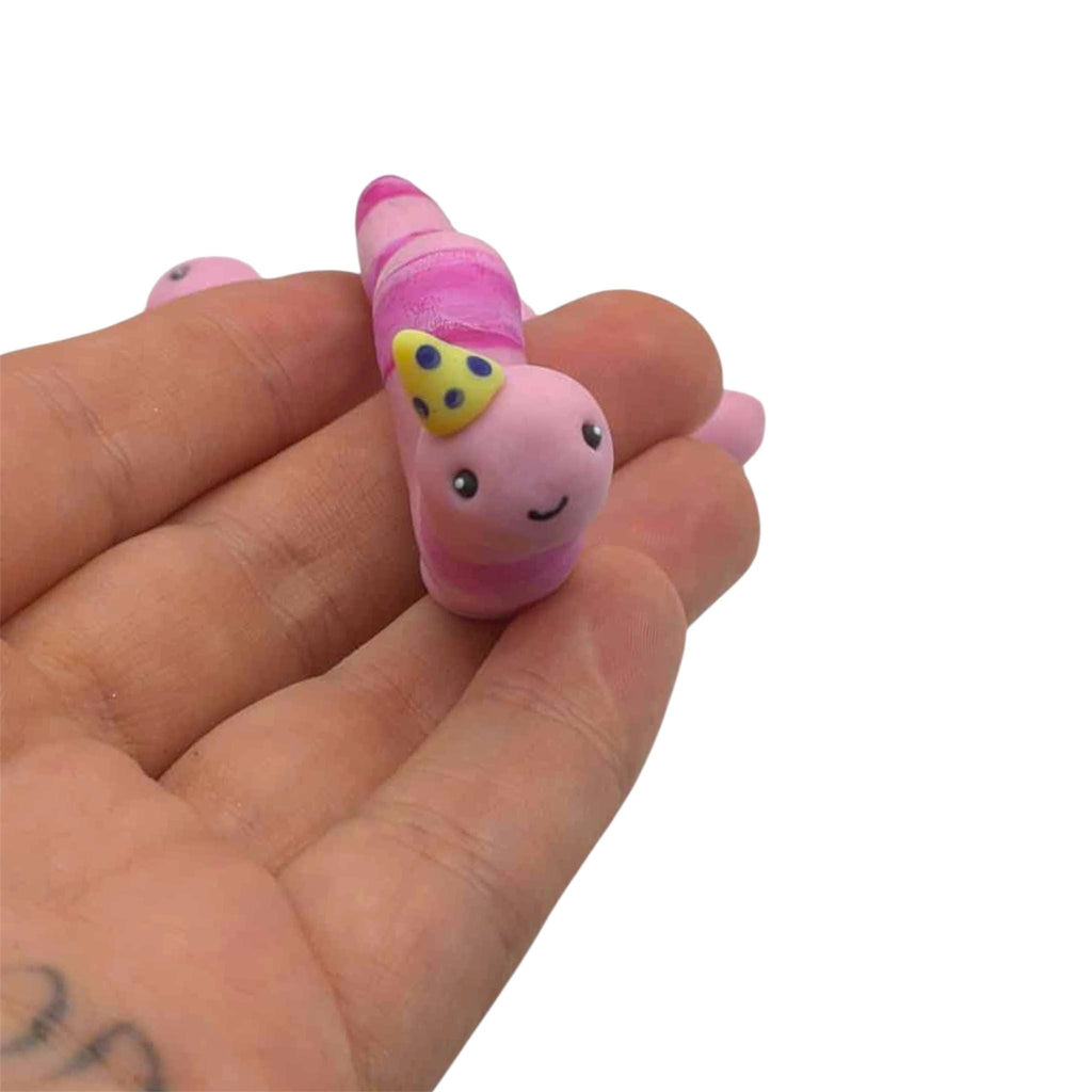 Pink worm with yellow party hat held on hand on white background 