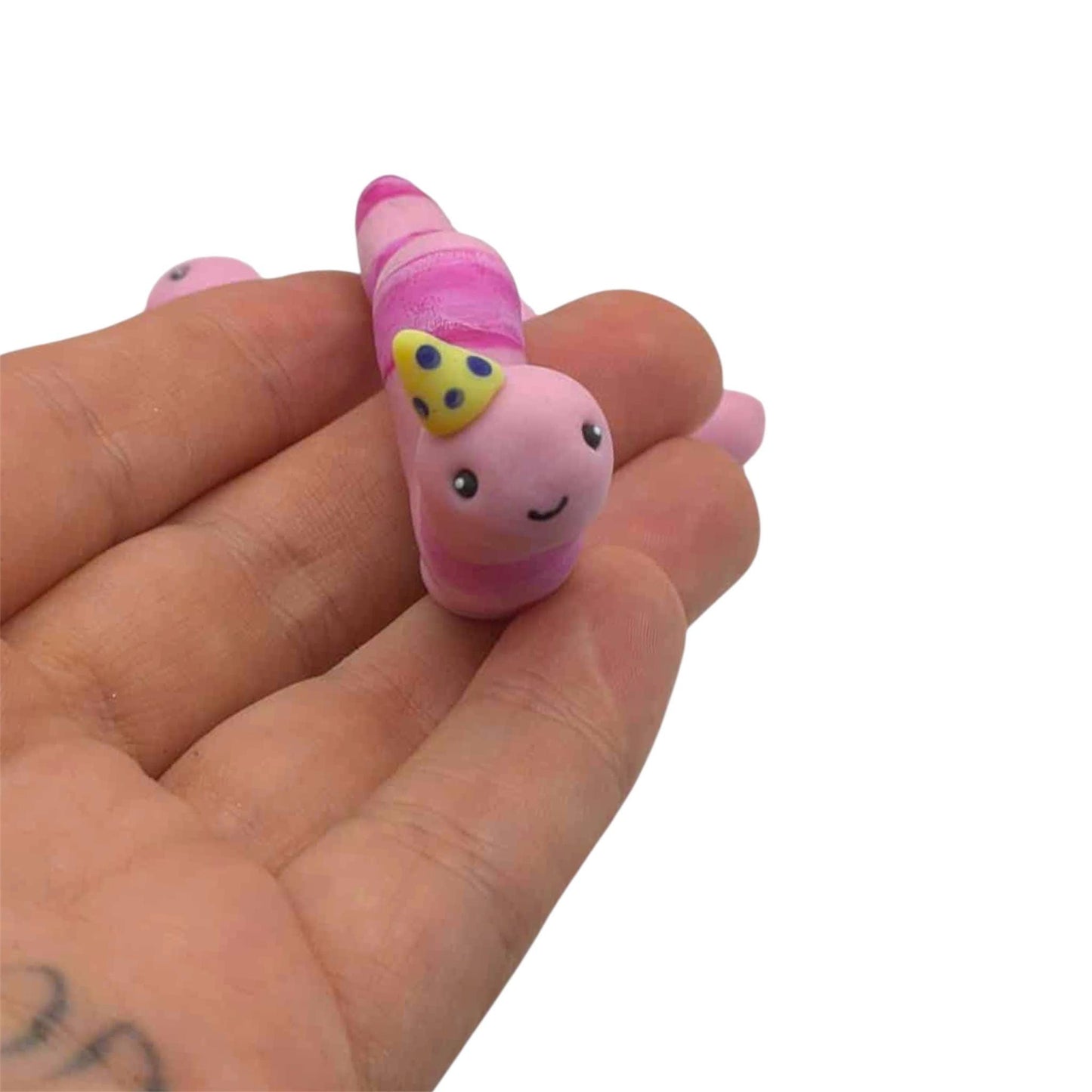 Pink worm with yellow party hat held on hand on white background 