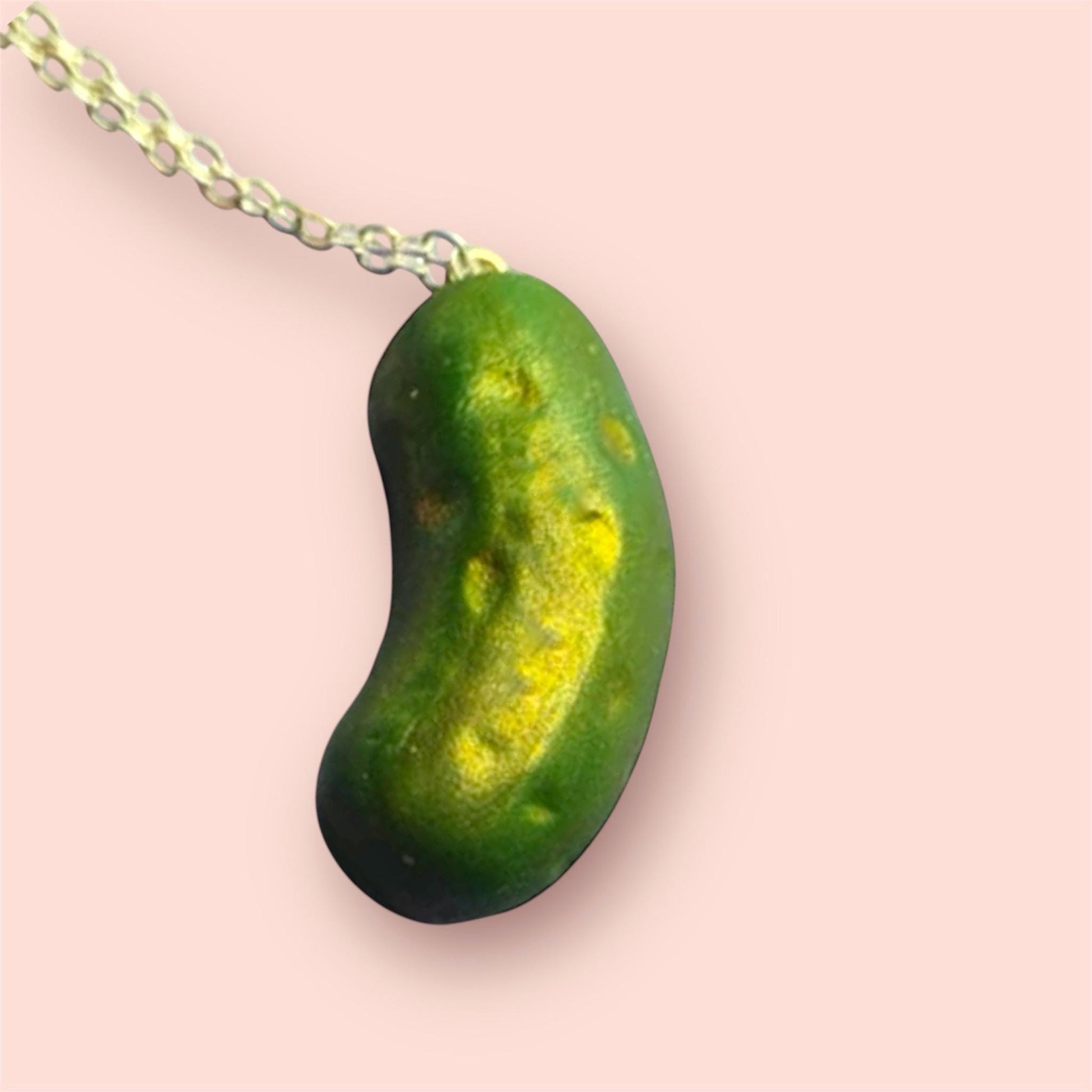 Green and yellow necklace pendant on a pink background