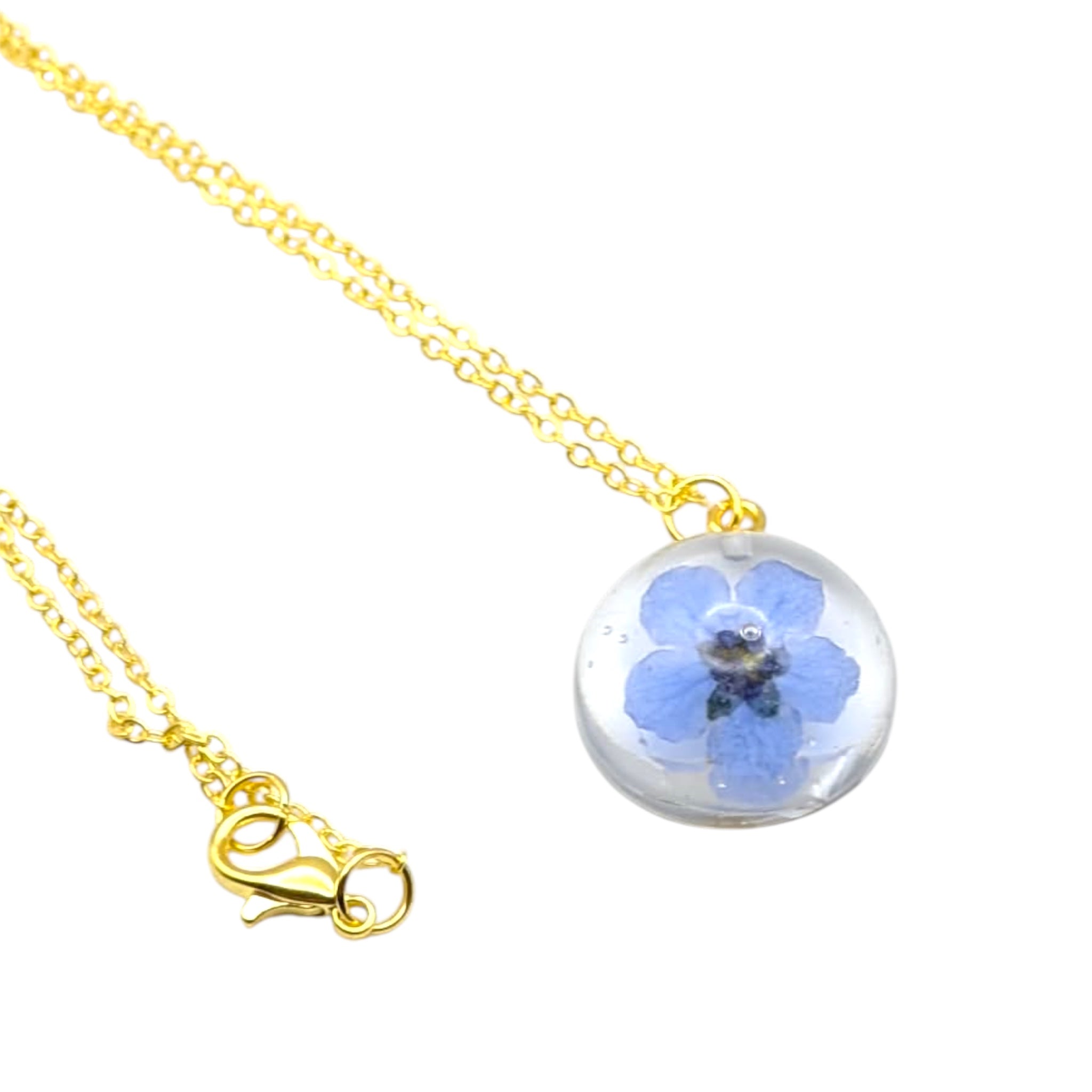 Necklace with a round pendant featuring a blue flower inside a clear sphere on a white background
