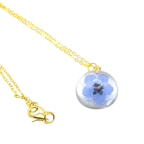 Necklace with a round pendant featuring a blue flower inside a clear sphere on a white background