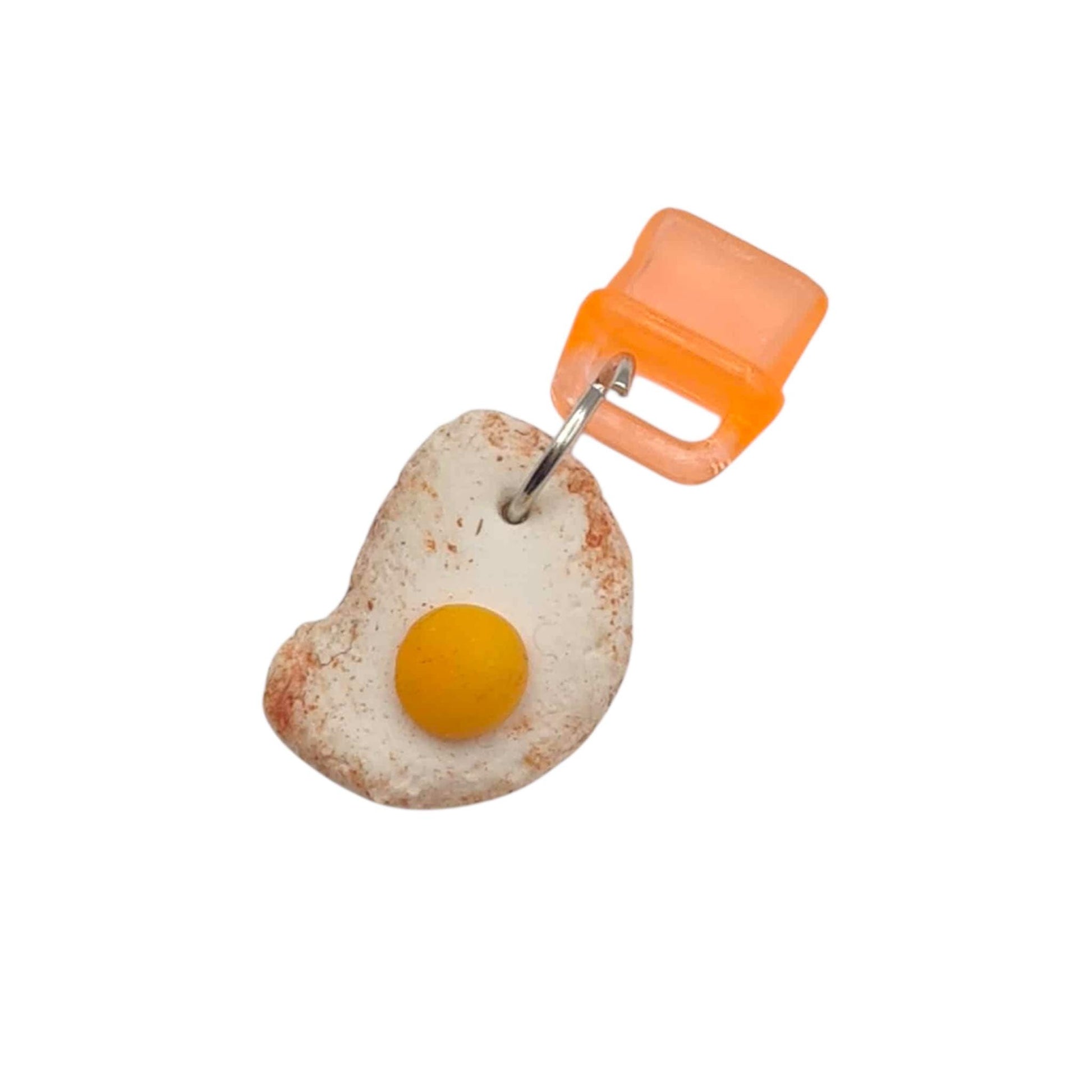 Fried egg-shaped keychain with an orange clip on a white background