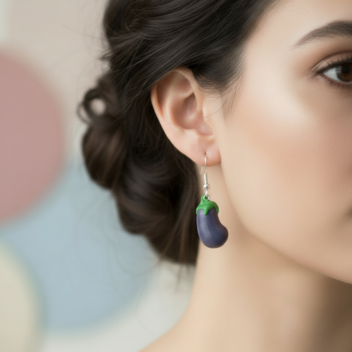 Close-up of a woman wearing an eggplant-shaped polymer clay earring with a blurred background