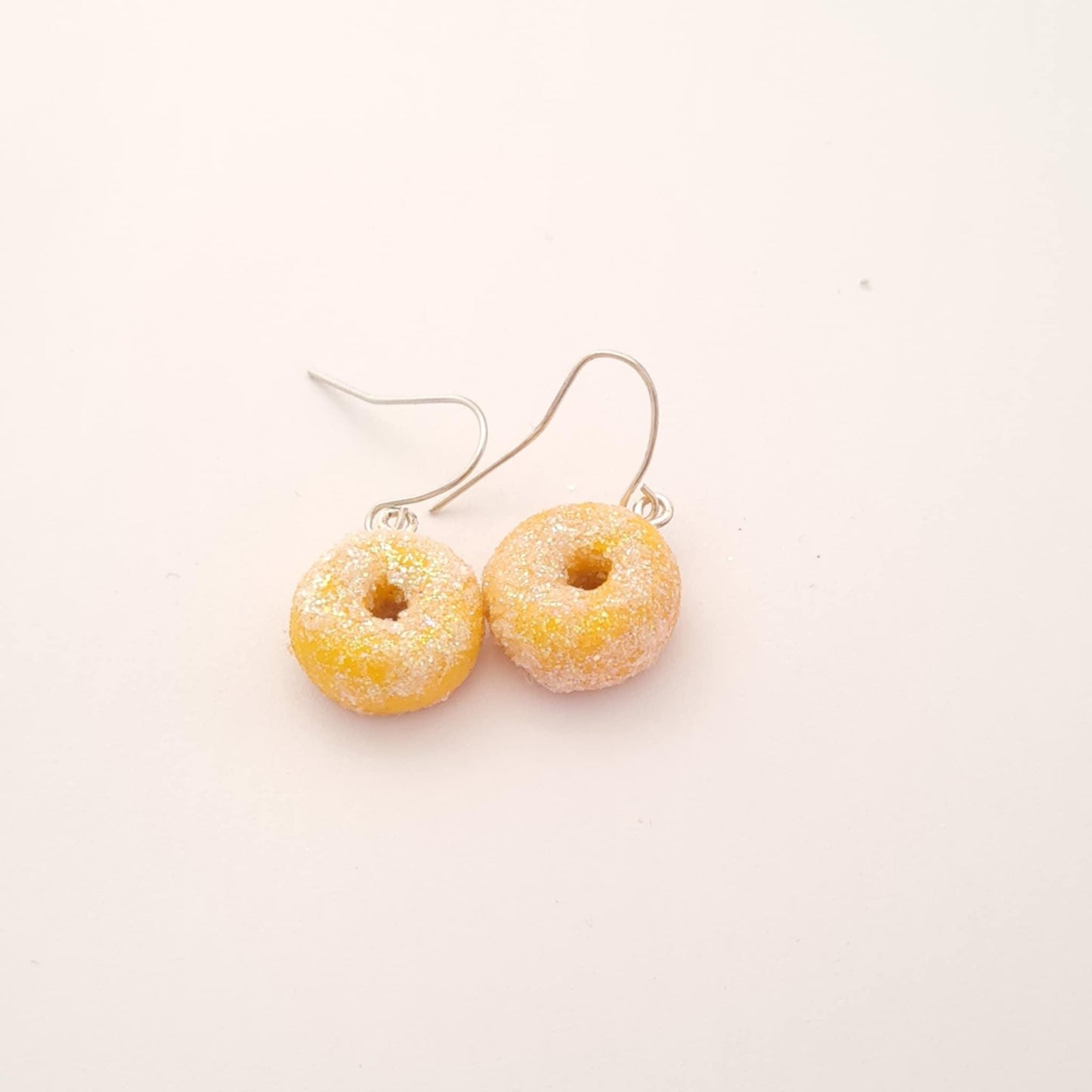 Donut-shaped earrings on a light pink background