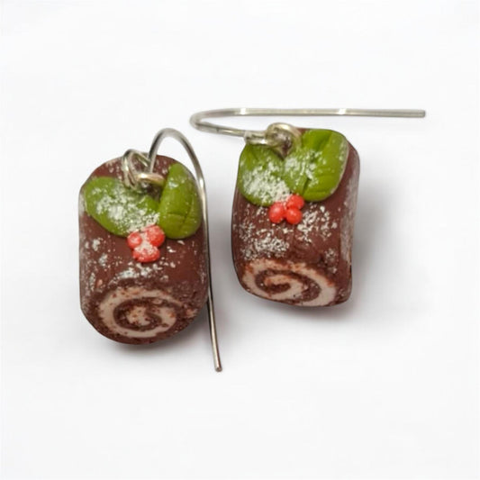 Chocolate roll cake earrings with green leaves and red flowers on a white background