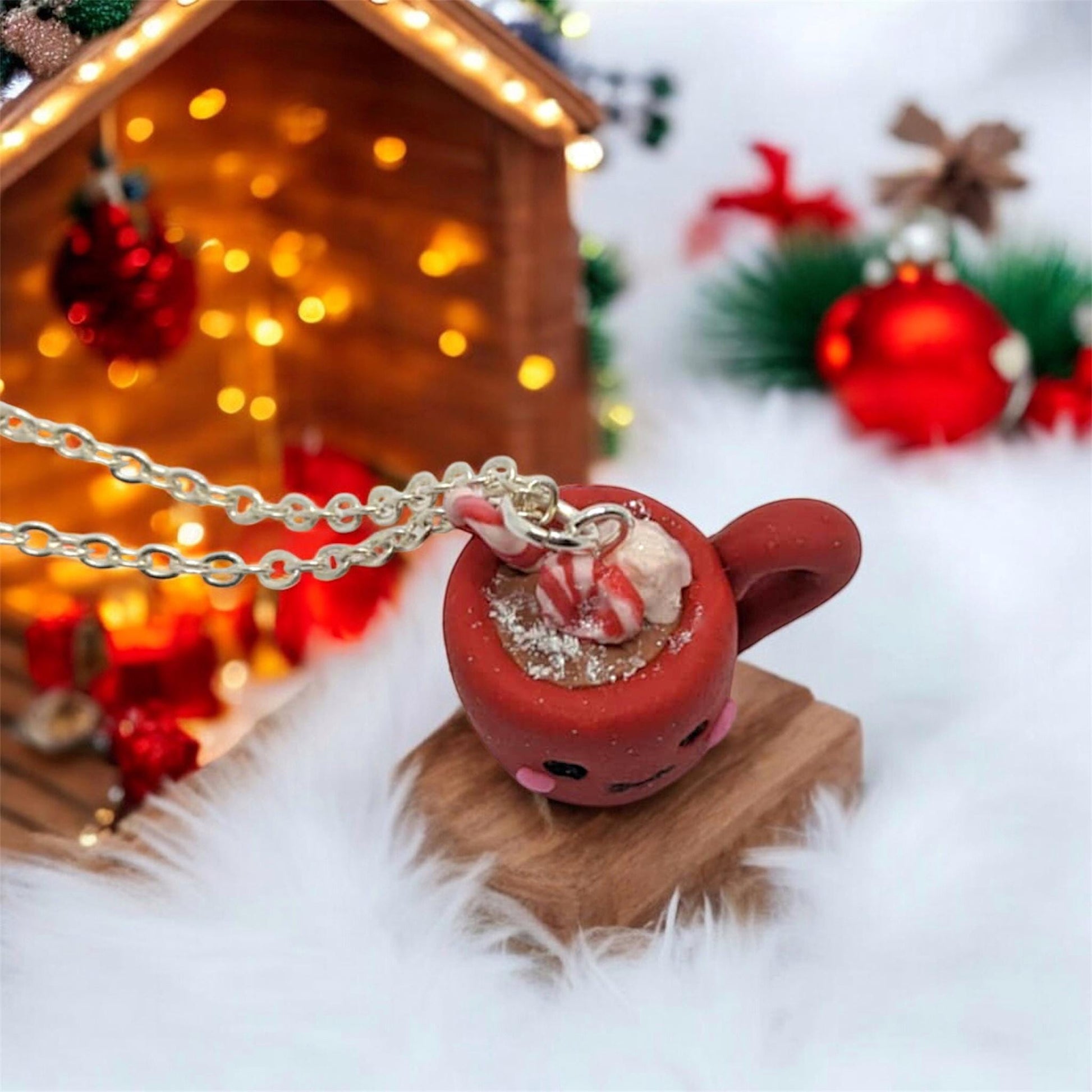 Red mug with candy cane and marshmallows on a wooden stand, Christmas decorations in the background