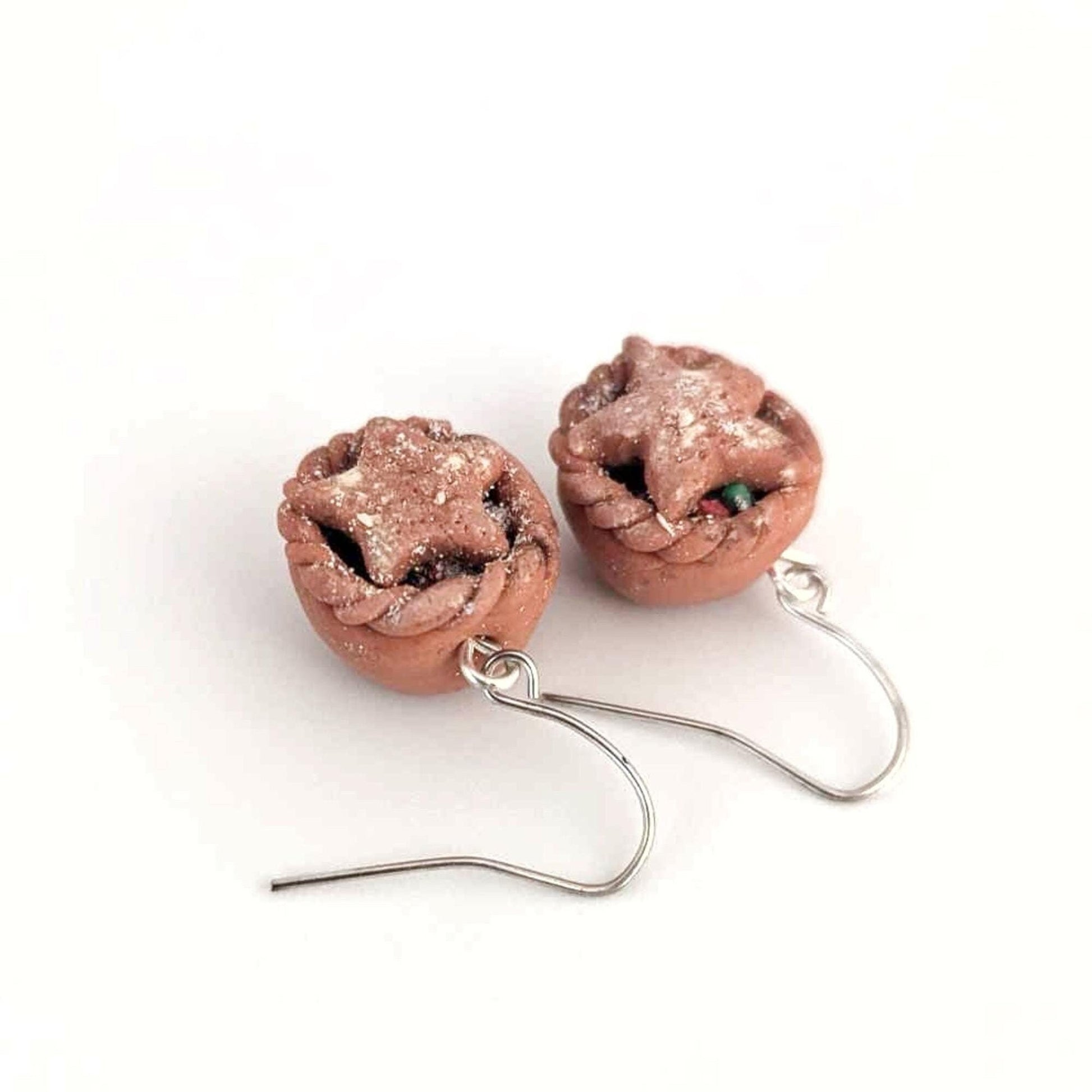 Pair of earrings with brown mince pies with stars on white background