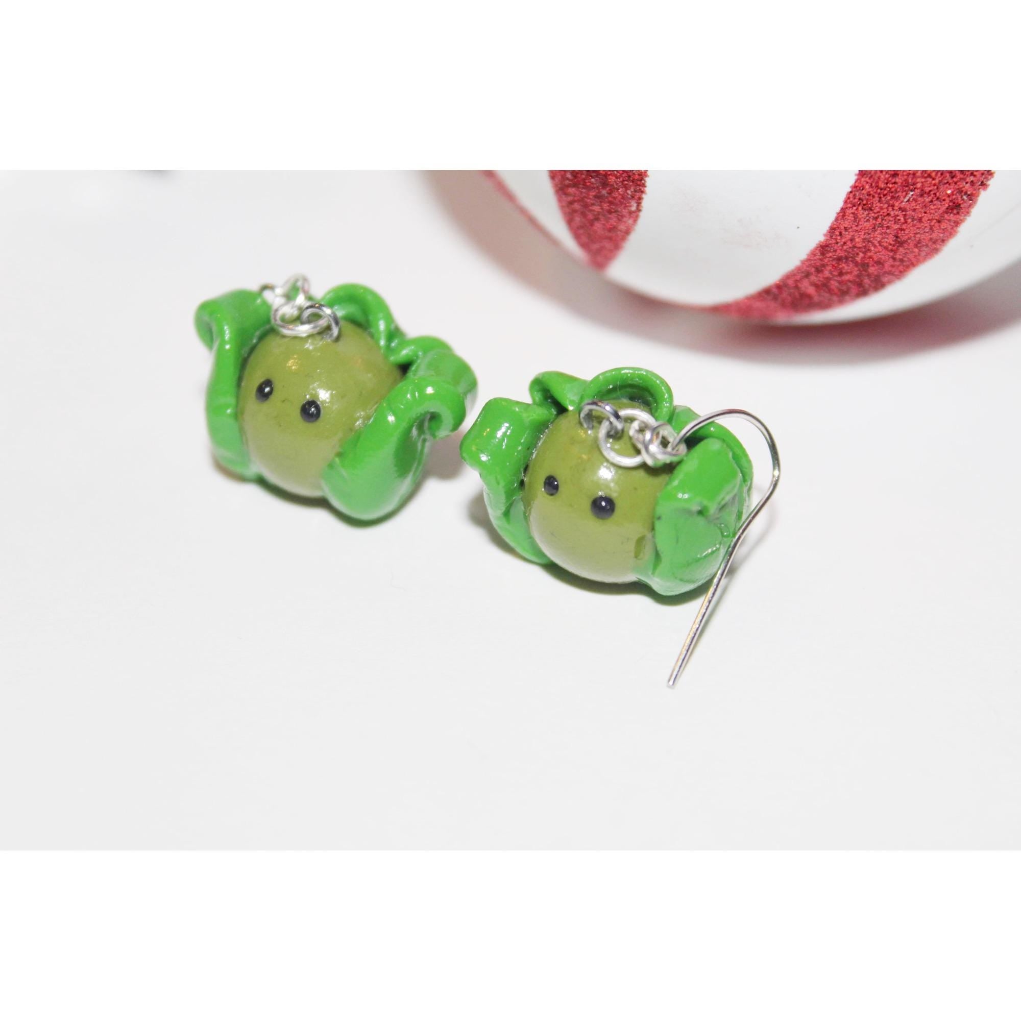 Green character-shaped earrings on a white background