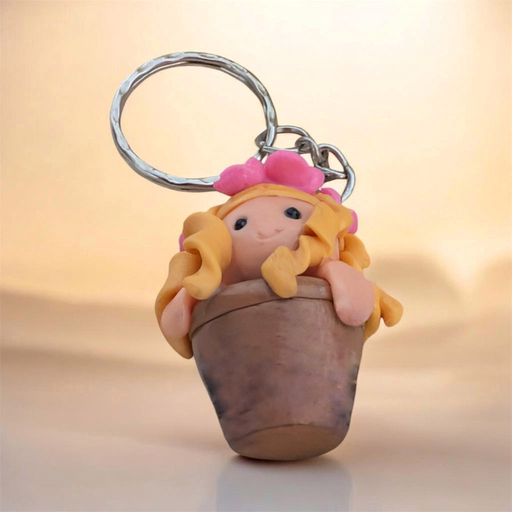 Keychain with a small figurine of a girl with blonde hair and pink flower on a beige background