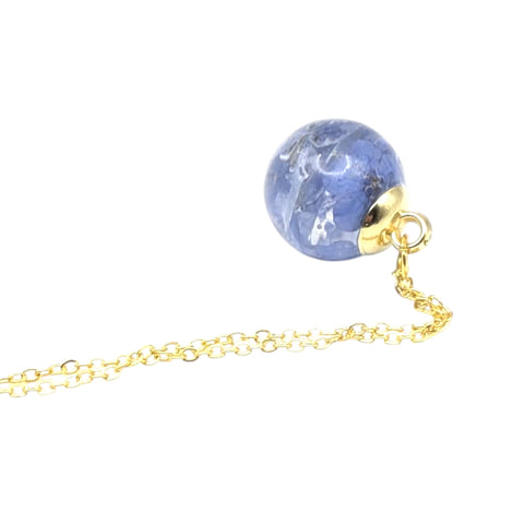 Gold necklace with a blue floral globe on a white background