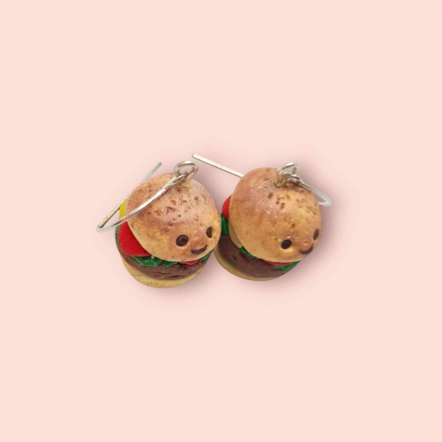 Burger-shaped earrings on a pink background