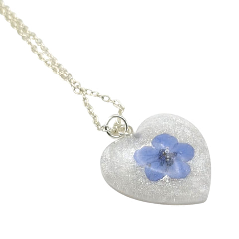 Heart-shaped pendant with a blue flower on a white background