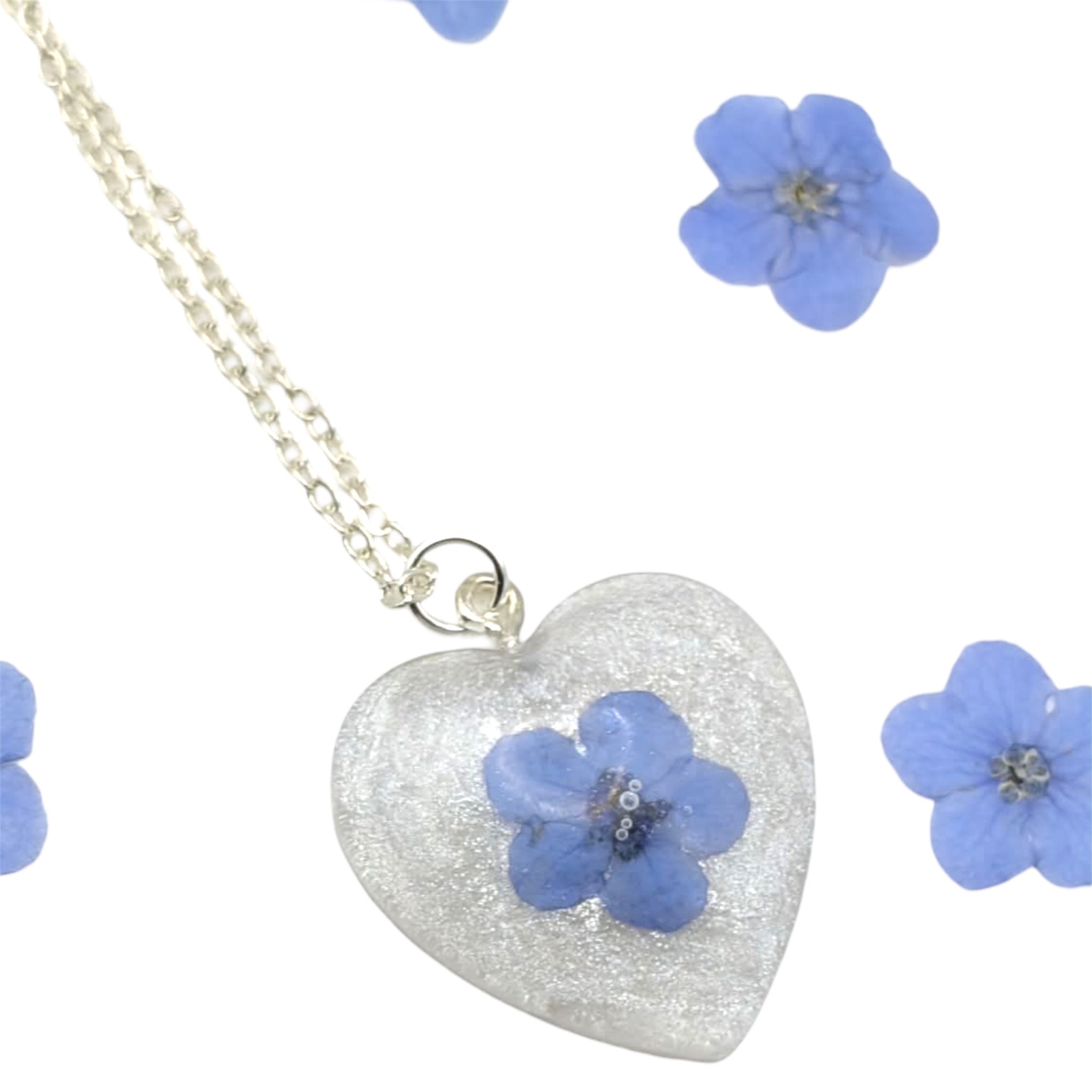 Heart-shaped pendant with a blue flower on a white background