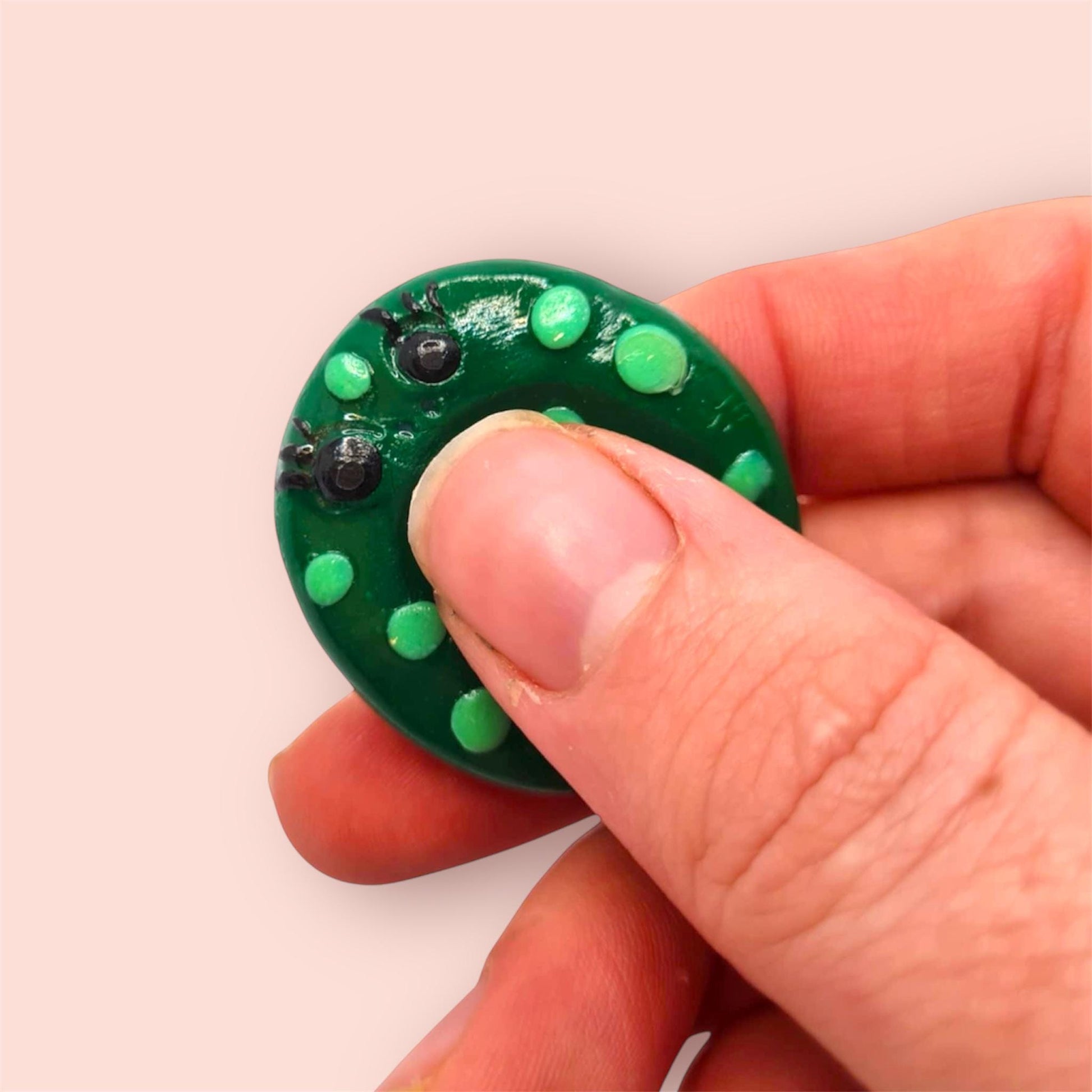 Hand holding a green circular object with embedded lights on a plain background