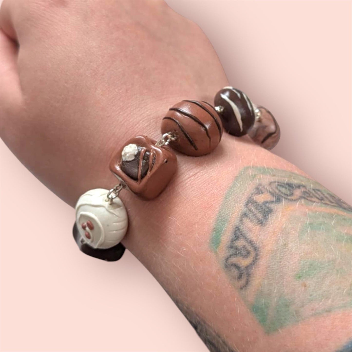 Beaded bracelet with brown, white, and black beads on a wrist with tattoos.