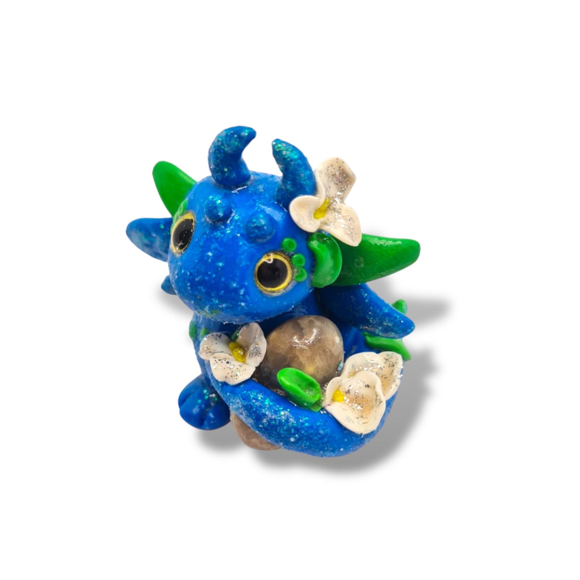Blue dragon figurine with green accents and flowers on a white background