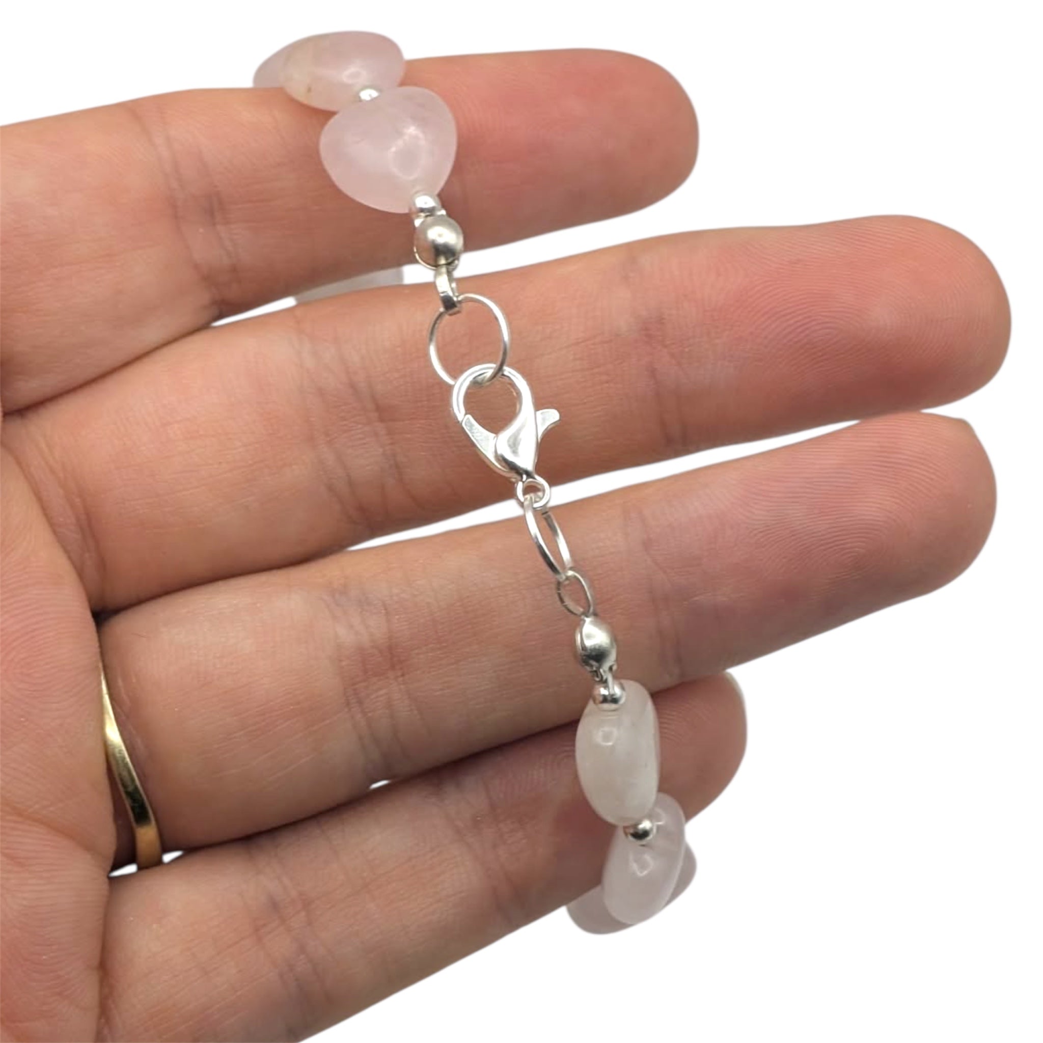 Rose quartz heart bracelet with silver plated chain held in hand showing adjustable clasp on white background