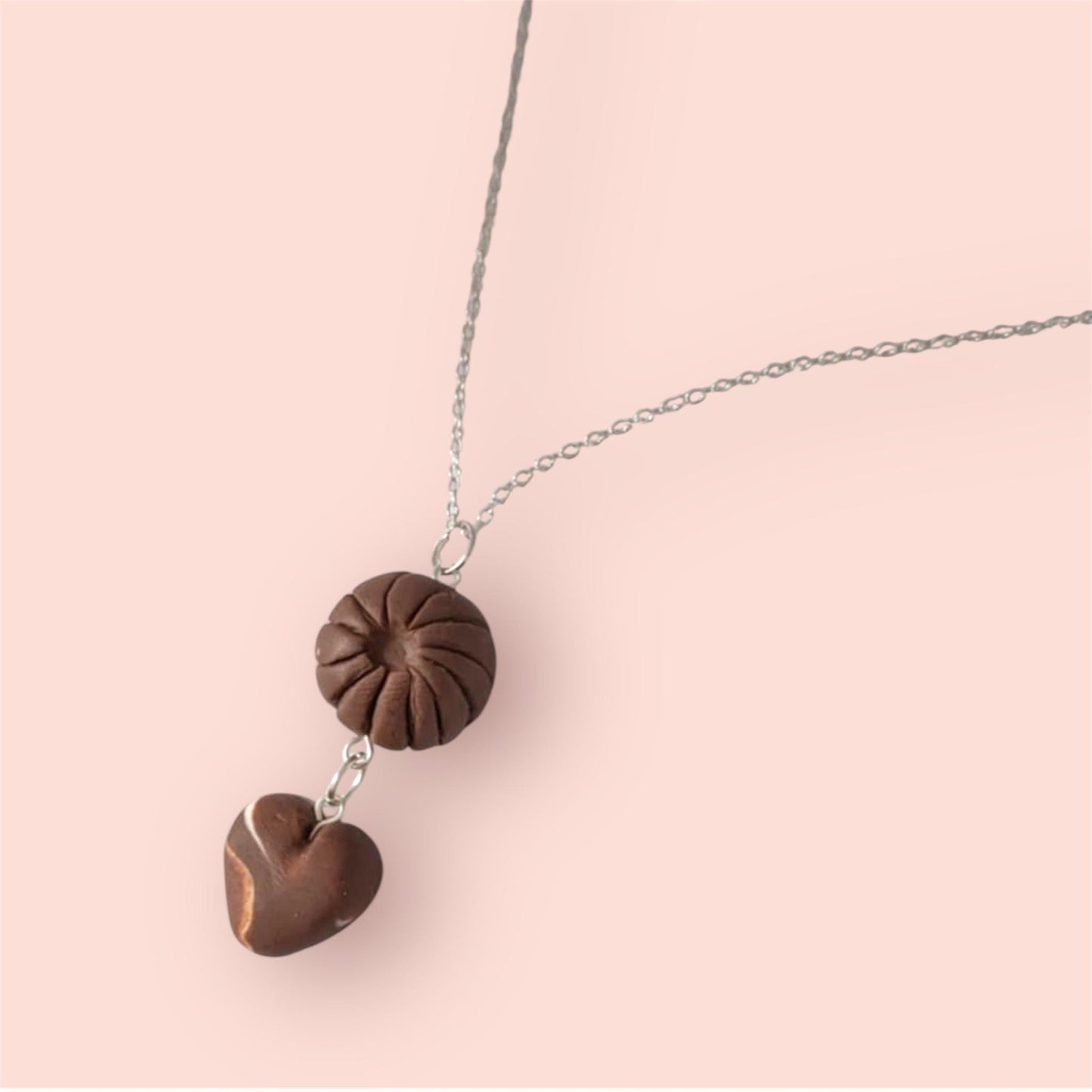 Necklace with brown heart-shaped pendants on a pink background