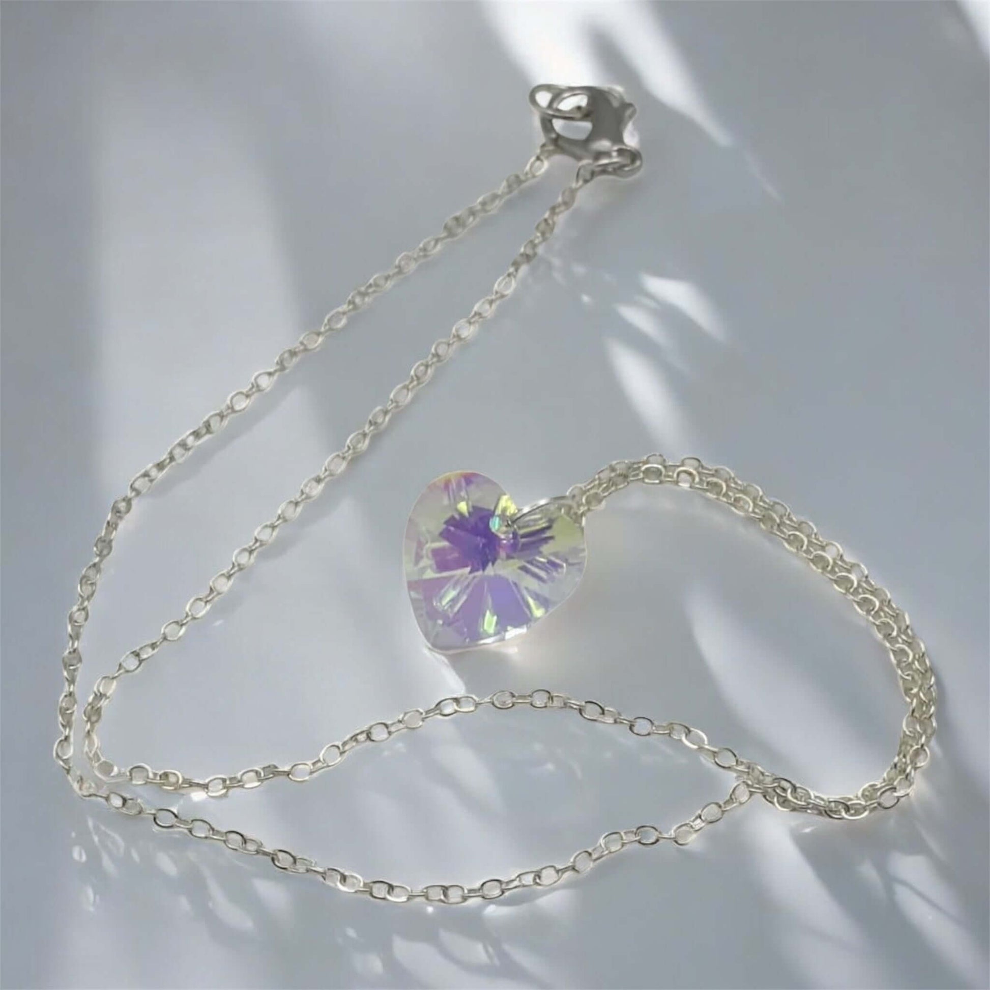 Silver chain necklace with a heart-shaped crystal pendant on a light background