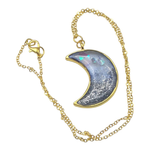 Gold chain necklace with a crescent moon pendant on a white background