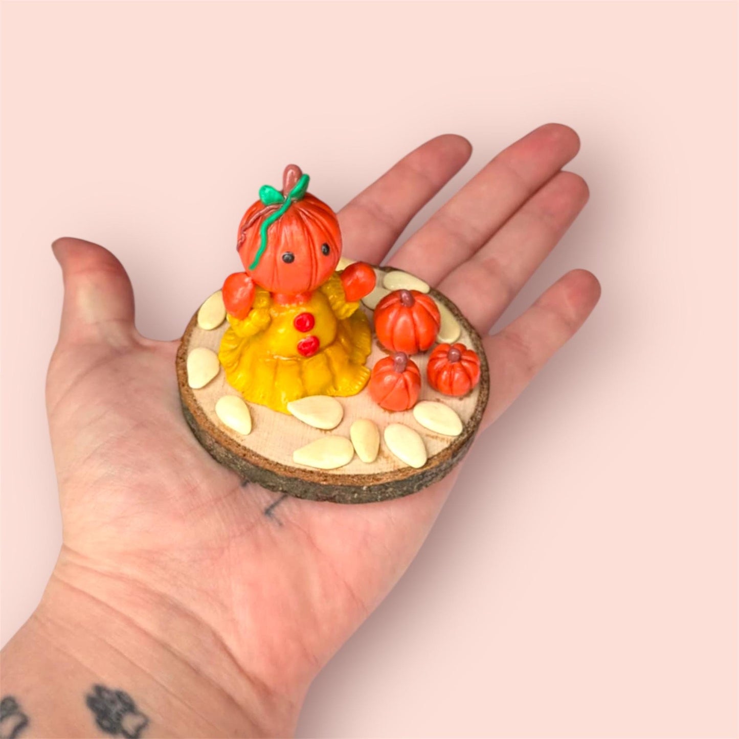Pumpkin figurine held in hand with wooden circular base 