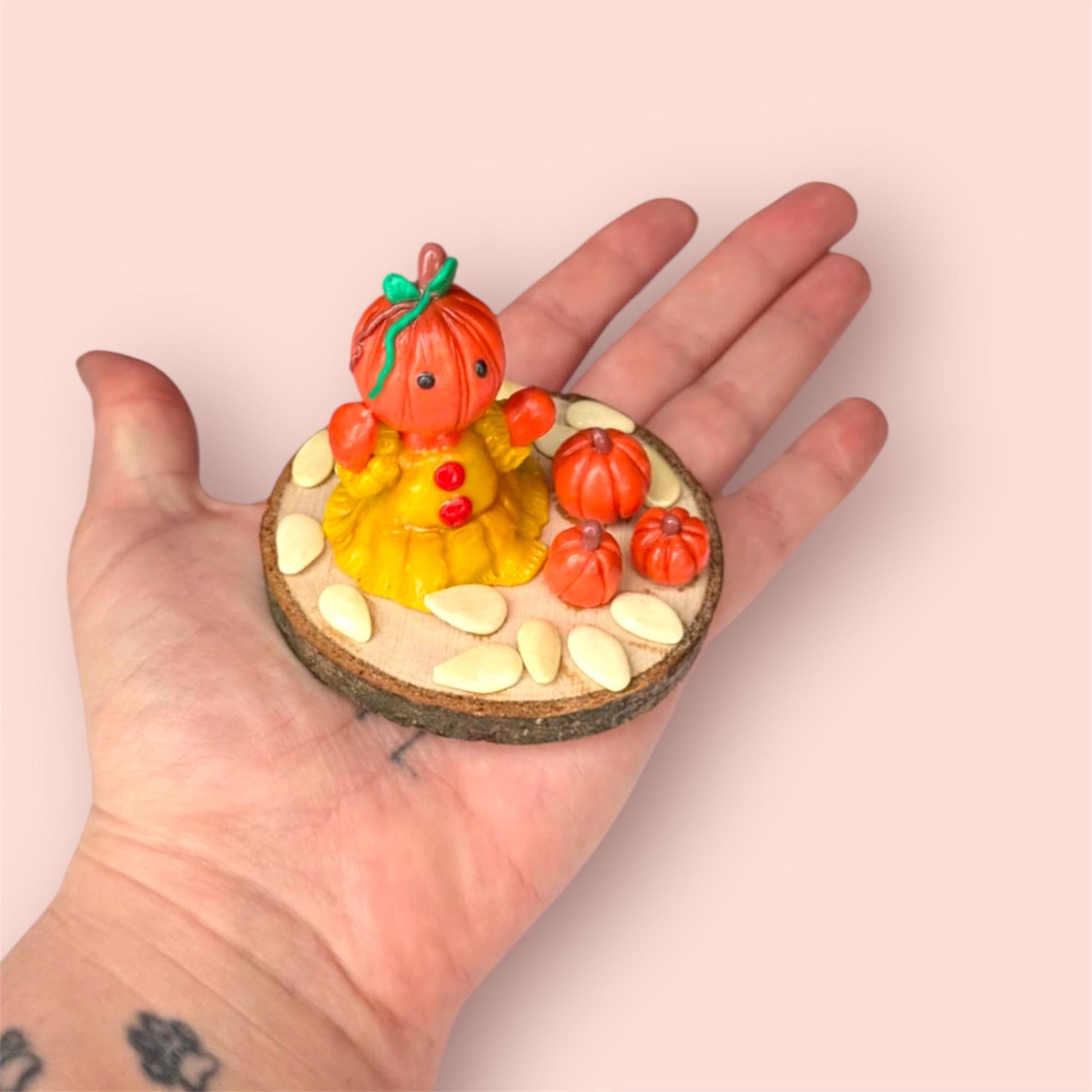 Pumpkin figurine held in hand with wooden circular base 