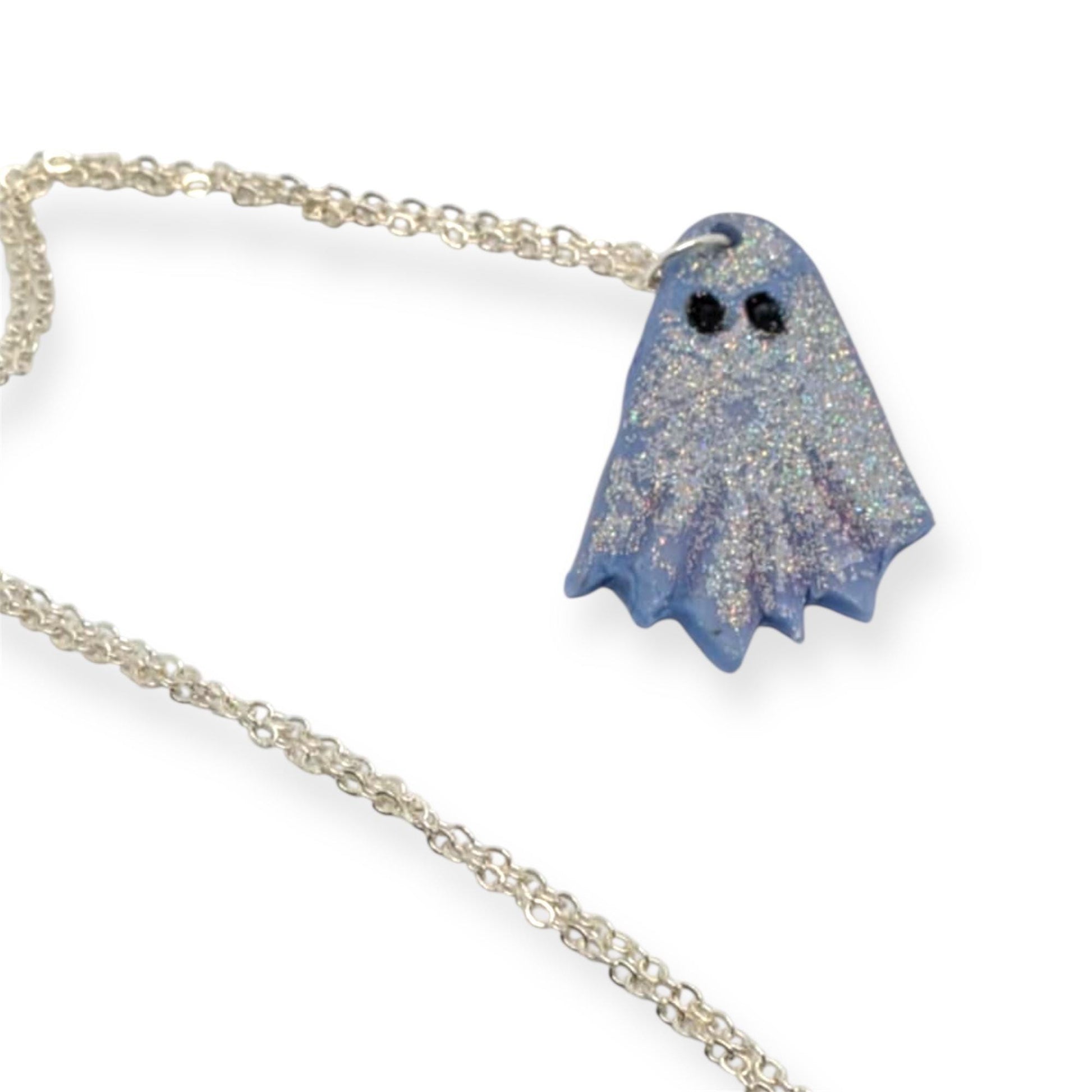 Blue glittery ghost pendant on a silver chain against a white background