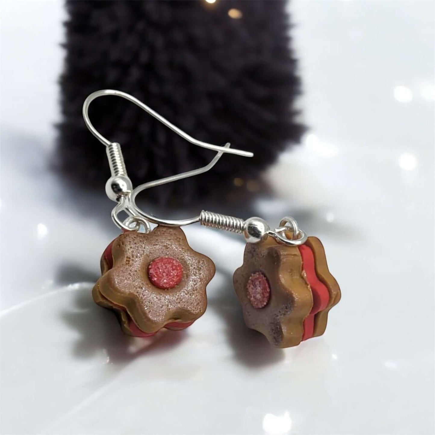 Earrings with cookie-shaped charms on a reflective surface