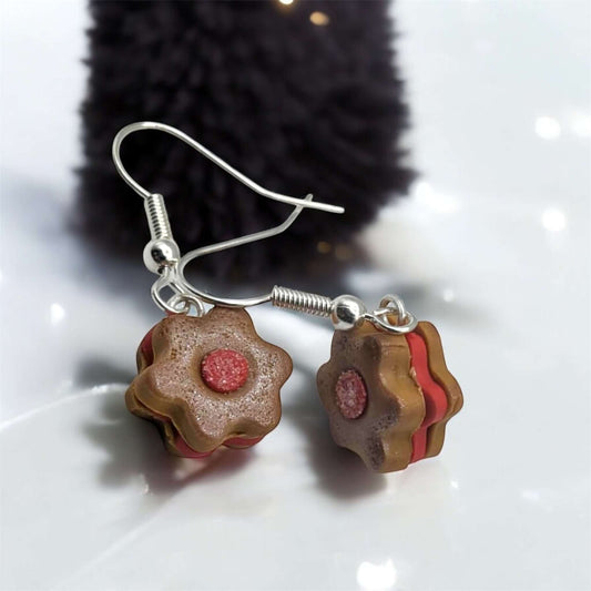 Earrings with cookie-shaped charms on a reflective surface