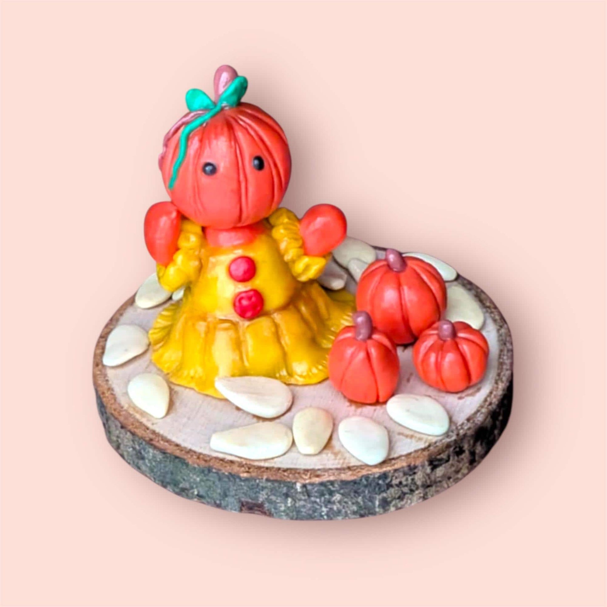 Pumpkin figurine with pumpkin seeds on a wooden base light pink background 