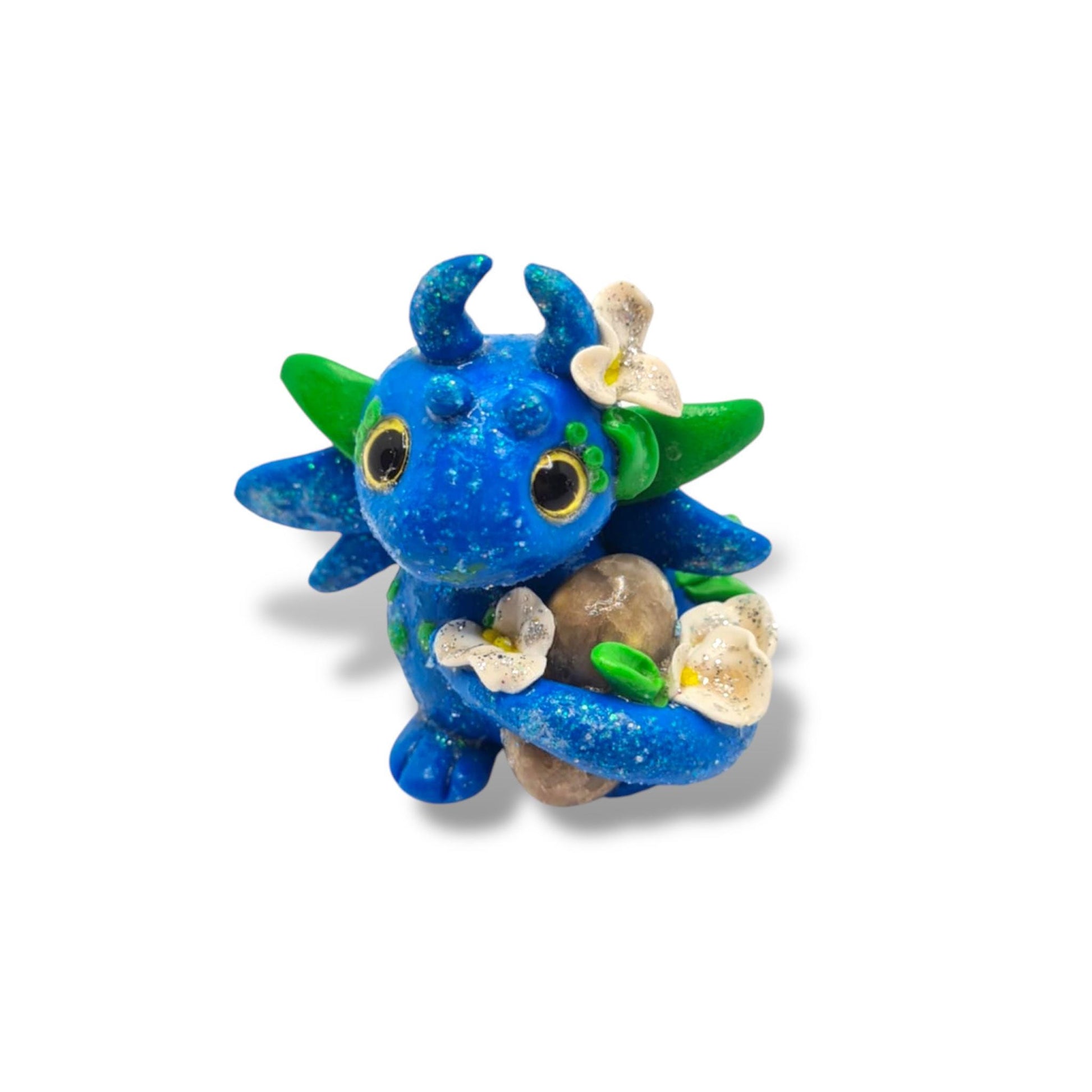 Blue dragon-like figurine with green accents and flowers on a white background
