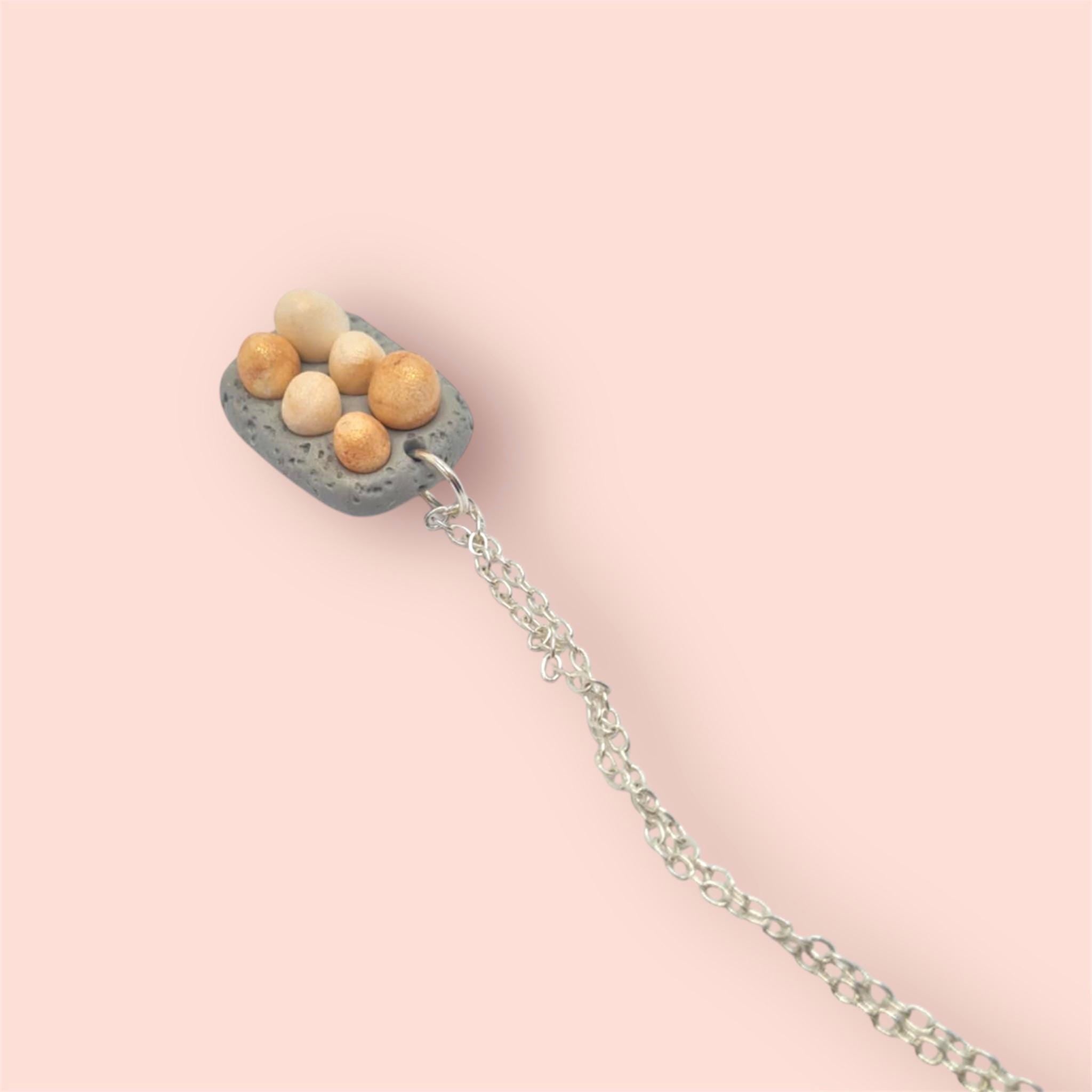 Polymer clay egg carton pendant on a silver chain on a pink background 