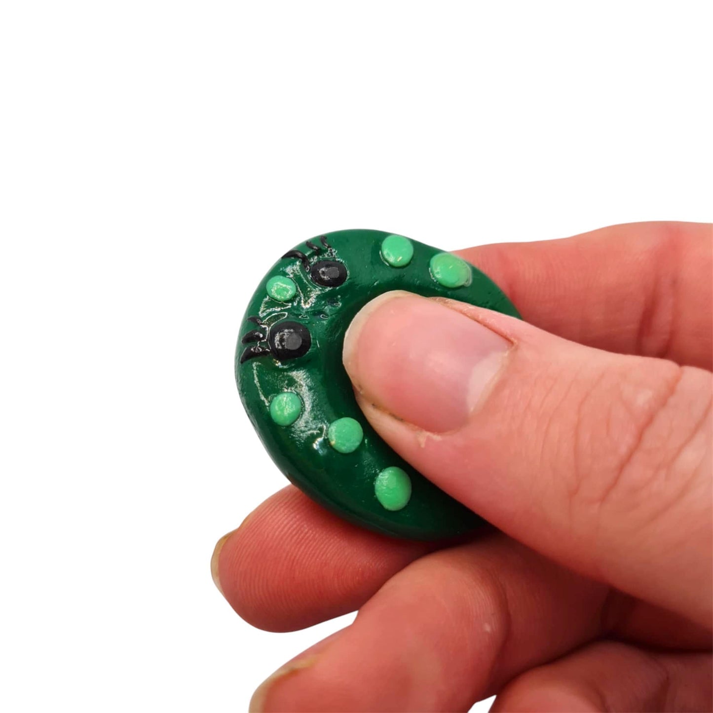 Hand holding a small green thumb buddy against a white background