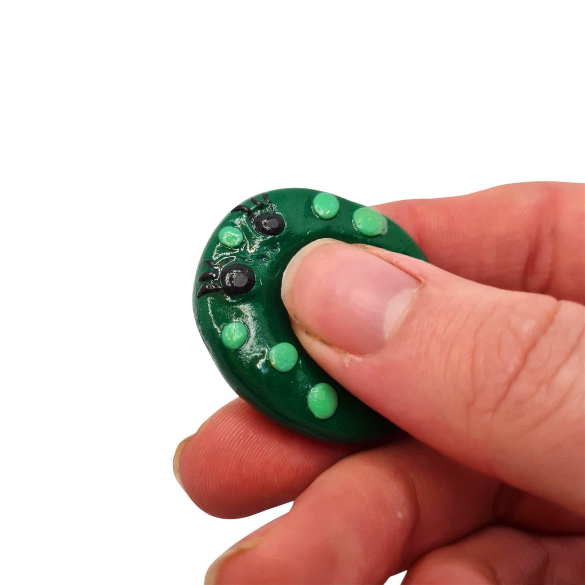 Hand holding a small green thumb buddy against a white background
