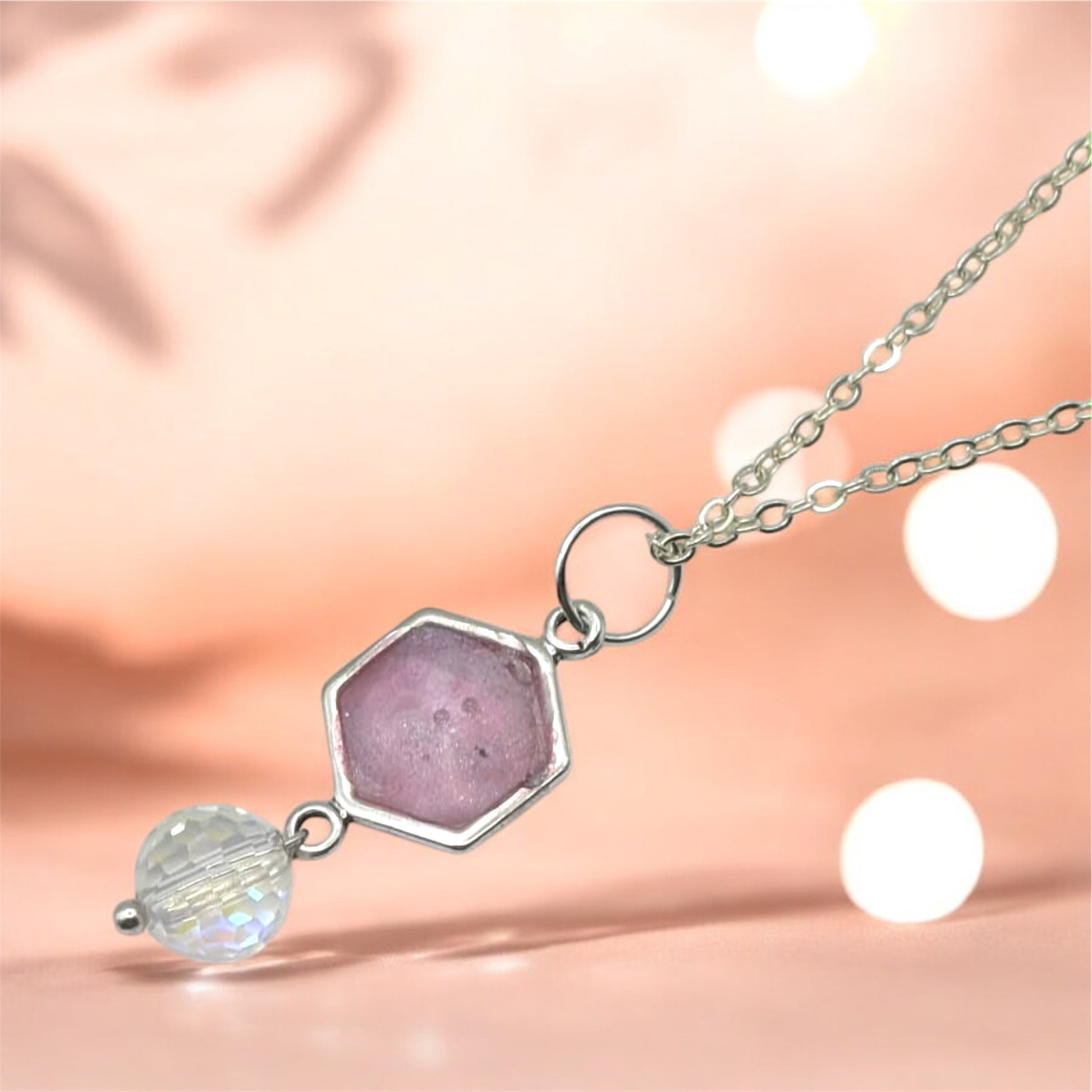 Necklace with a pink pendant and crystal bead on a soft pink background