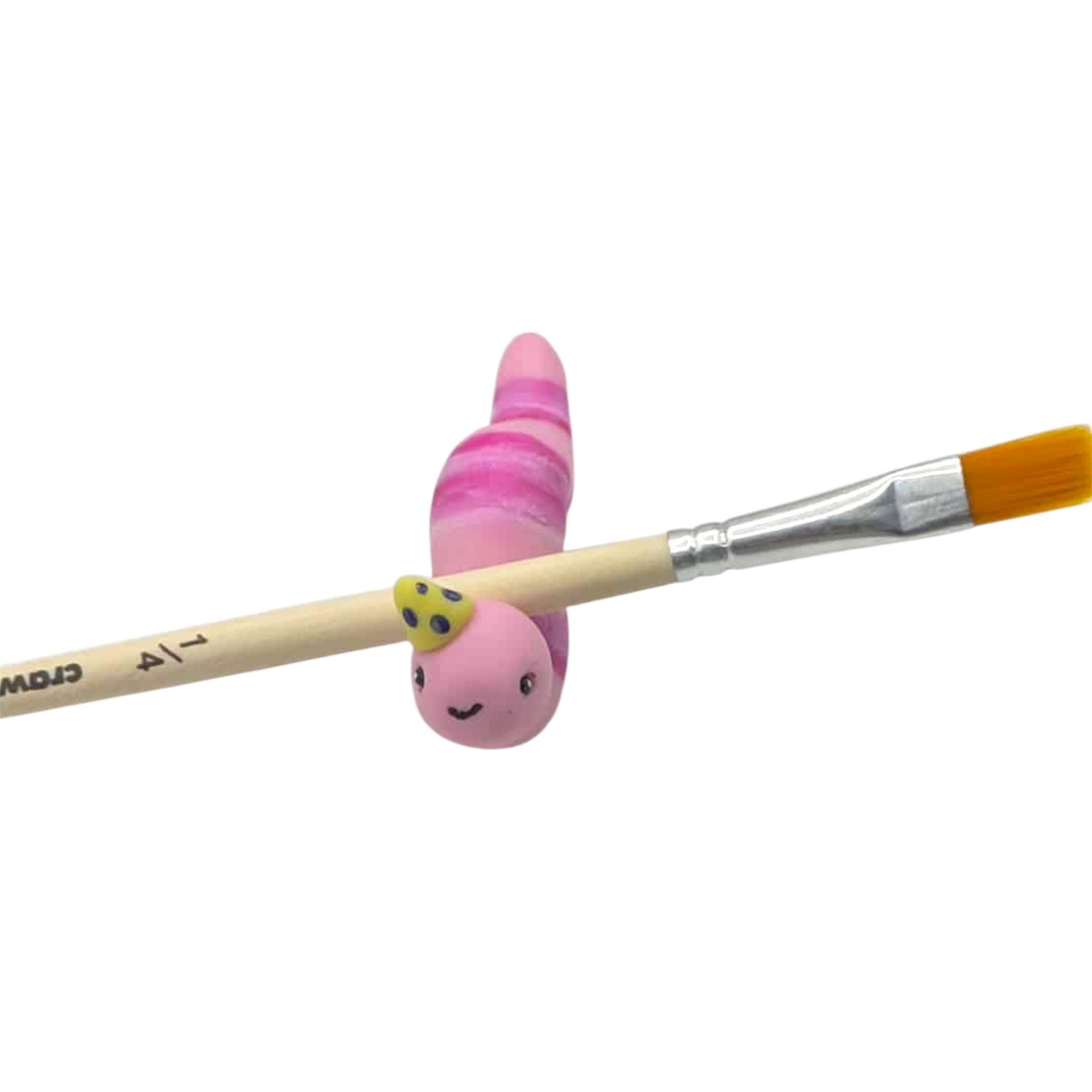 Pink worm figurine paintbrush rest with a white background