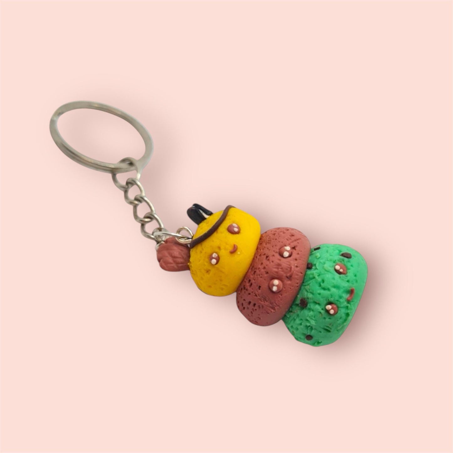 Colorful keychain with three textured stones on a pink background