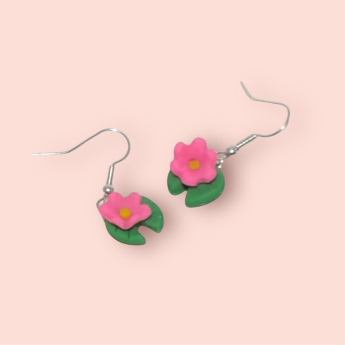 Flower-shaped earrings on a pink background