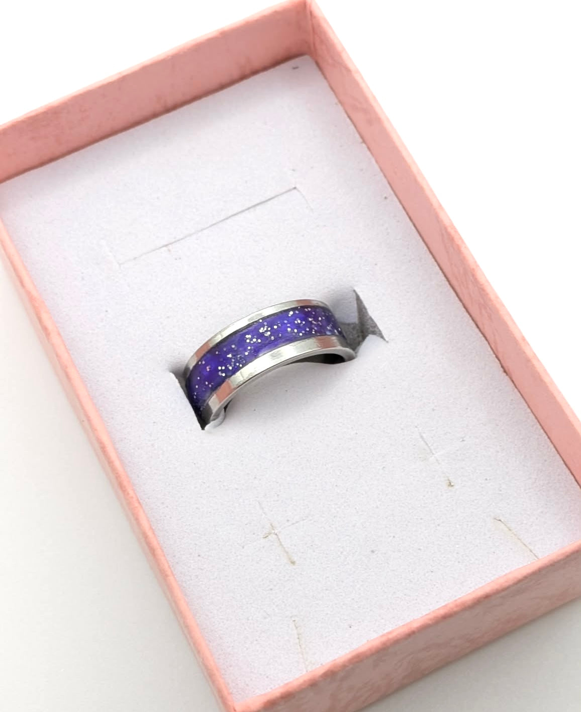 Silver ring with purple glittery design in a pink box