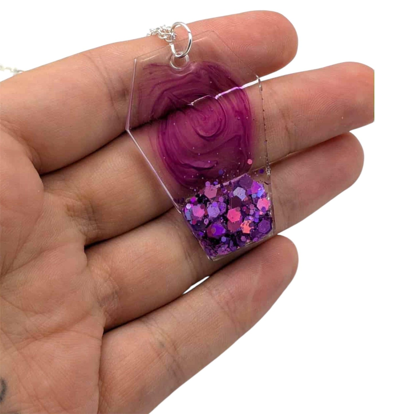 Hand holding a purple pendant with glittery interior