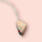 Necklace with a sand wedge pendant on a pink background